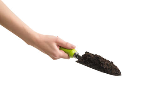 Little green shovel with soil in woman hand isolated on white background.
