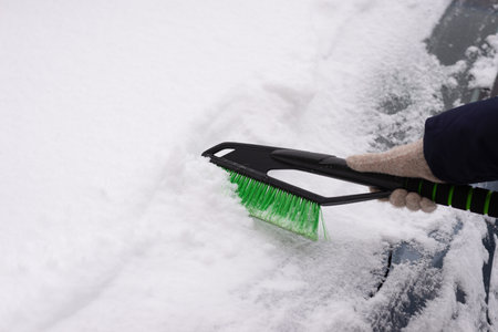 Snow removal, car in snow. Woman cleans the car from snow.の写真素材