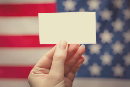 Empty card in woman hand. Copy space. American flag background.