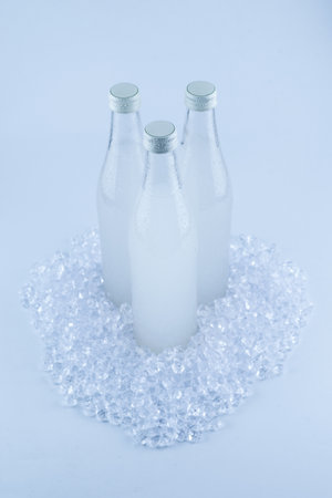 A white bottle with a soda drink on ice isolated on a white background.