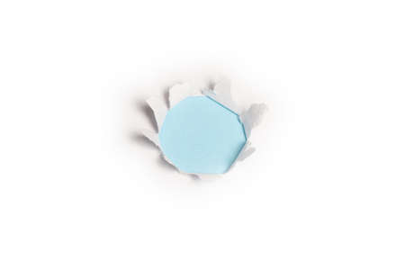 A hole in a white paper on a blue background, copy space.