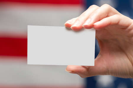 Empty card in woman hand. Copy space. American flag background.の写真素材