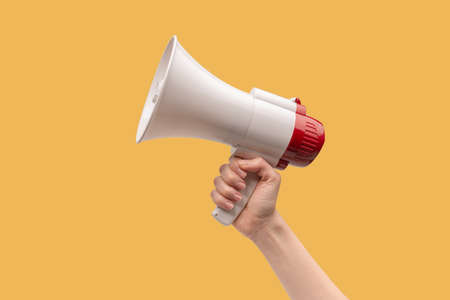 Megaphone in woman hands on a white background. copyspace.