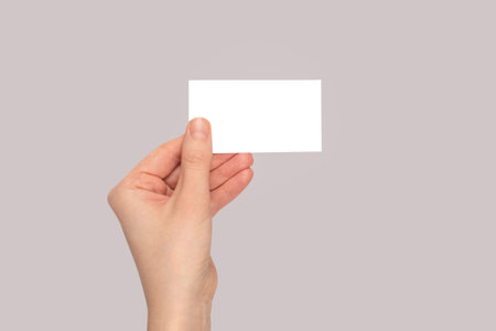 Empty card in woman hand. copyspace. gray background.の写真素材