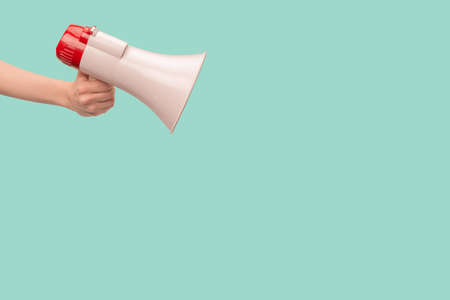 Megaphone in woman hands on a green background. copyspace.の写真素材