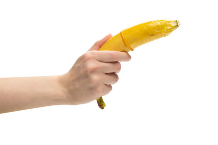 Woman put on a condom on a banana. isolated on a white background.の写真素材