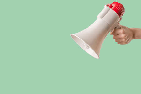 Megaphone in woman hands on a green background. copyspace.の写真素材