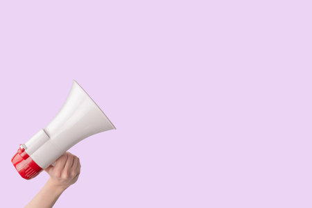 Megaphone in woman hands on a pink background. copyspace.の写真素材