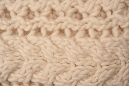 A fragment of beige knitted fabric, knitted from white sheep wool. Knitted background.