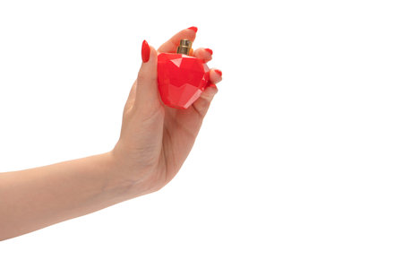 Red bottle of perfume in woman hand with red nails isolated on a white background. copyspace.の写真素材