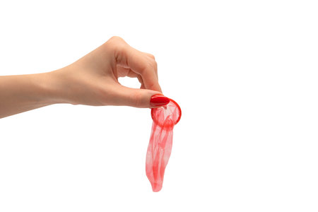 A red condom in a woman hand with red nails isolated on a white background.の写真素材