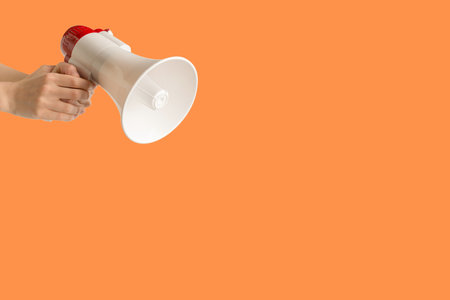 Megaphone in woman hands on an orange background. copyspace.の写真素材