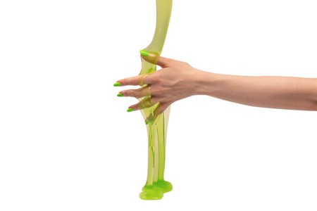 Green slime toy in woman hand with green nails isolated on a white background.の写真素材