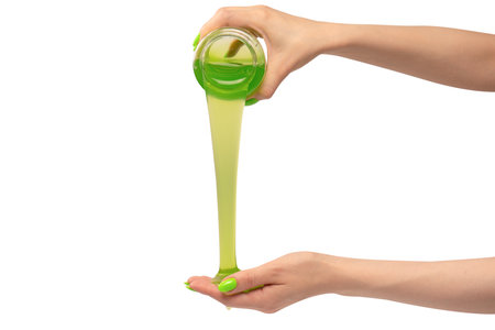 Green slime toy in woman hand with green nails isolated on a white background.の写真素材