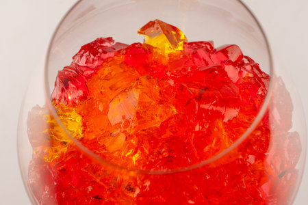 Sweet fruit jelly dessert in a glass isolated on a white background. gelatin cubes.の写真素材