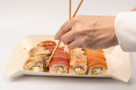 Food delivery. A box with sushi rolls in woman hands isolated on a white background.の写真素材