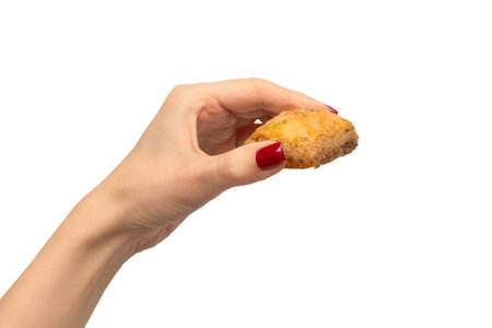 Delicious sweet baklava in woman hand with red nails isolated on a white background. Top view.