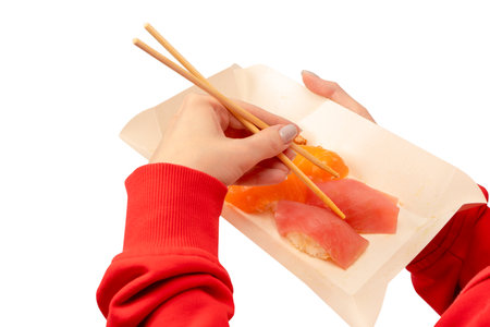 Food delivery. A box with sushi rolls in woman hands isolated on a white background.の写真素材