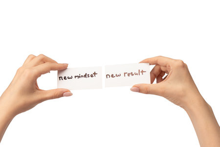 New mindset - new result text on a card in a woman hand isolated on a white background.の写真素材