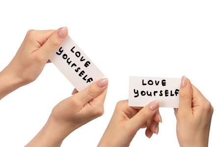 Love yourself text on a card in a woman hand isolated on a white background.