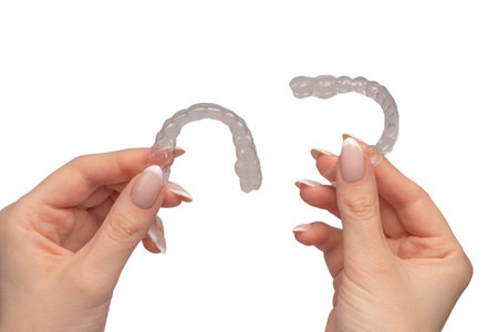 Transparent mouth guard in a woman's hand isolated on a white background.