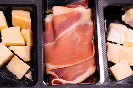 A plate with snacks for wine. Cheese, olives, salami, jamon isolated on a white backgrund.の写真素材