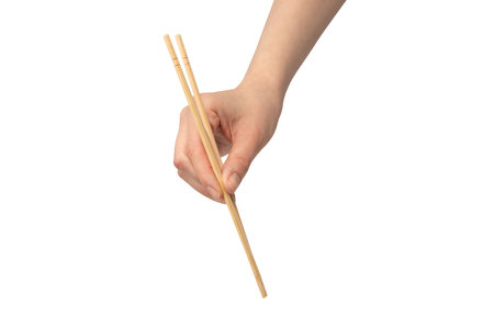 Female hand holding wooden sushi chopsticks isolated on a white background.の写真素材