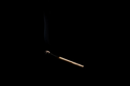 Lit and falling match on a black background.の写真素材