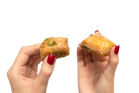 Delicious sweet baklava in woman hand with red nails isolated on a white background. Top view.の写真素材