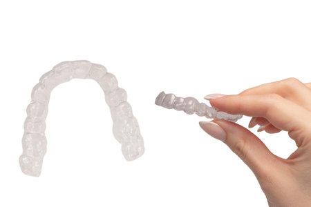 Transparent mouth guard in a woman's hand isolated on a white background.