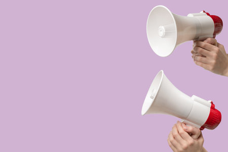 Megaphone in woman hands on a lilac background. Copy space.の写真素材