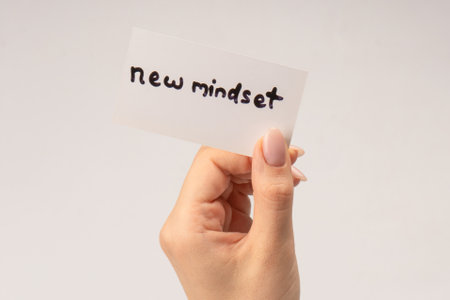 New mindset - new result text on a card in a woman hand isolated on a white background.の写真素材