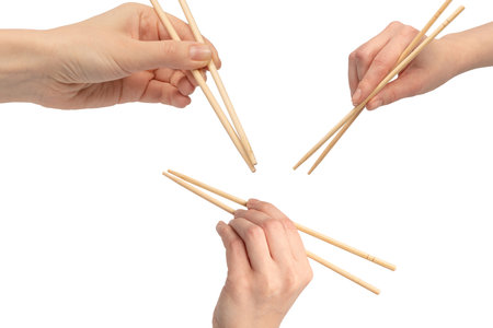 Female hand holding wooden sushi chopsticks isolated on a white background.の写真素材