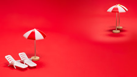 Two sun loungers and red umbrellas on a red background. Copy space.の写真素材
