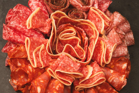 Different kinds of meat cuts on a board. On a black background.