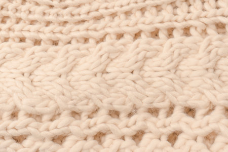 A fragment of beige knitted fabric, knitted from white sheep wool. Knitted background.