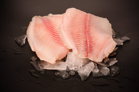 Fresh tilapia fillet on ice on black backgroundの写真素材