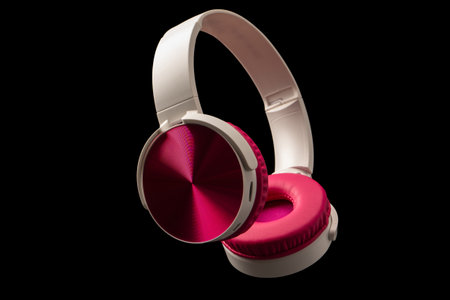 Pink and white headphones isolated on a black background.の写真素材