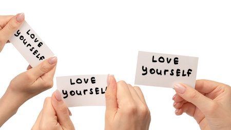Love yourself text on a card in a woman hand isolated on a white background.の写真素材