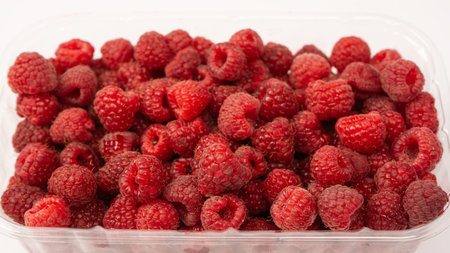 Raspberry in plastic container isolated on white background.