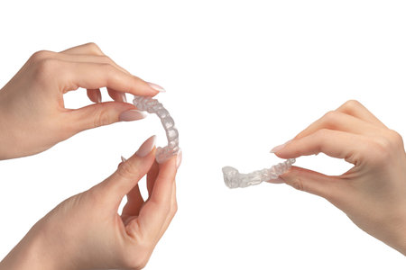 Transparent mouth guard in a woman's hand isolated on a white background.