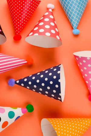 Colorful birthday caps on orange background. Top view.