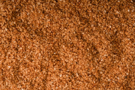 Close up texture of dry organic buckwheat flakes. Natural healthy whole grain food background with rustic cereal pattern, full frame macro shot.