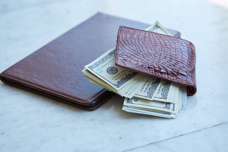 tablet on the table in a leather pouch and a leather purse with moneyの写真素材