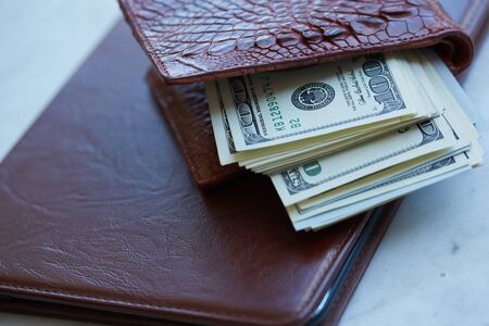 tablet on the table in a leather pouch and a leather purse with moneyの写真素材