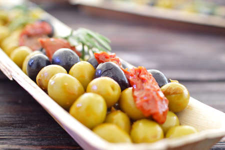 black and green olives, herbs, sun-dried tomatoes in an oblong dishの写真素材