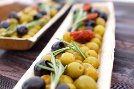 black and green olives, herbs, sun-dried tomatoes in an oblong dishの写真素材