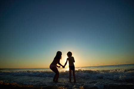 boy and girl on the sea at sunsetの写真素材
