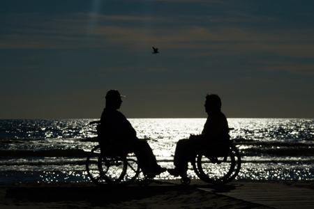 handicapped wheelchair by the sea at sunsetの写真素材