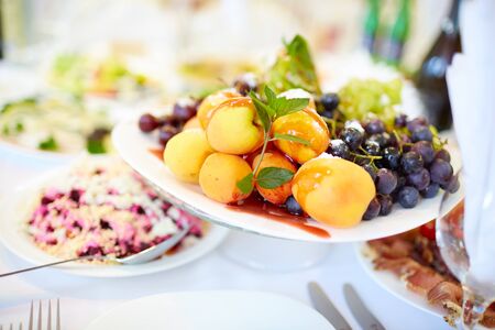 tasty fruit on a plate with pears, grapes, apricotsの写真素材
